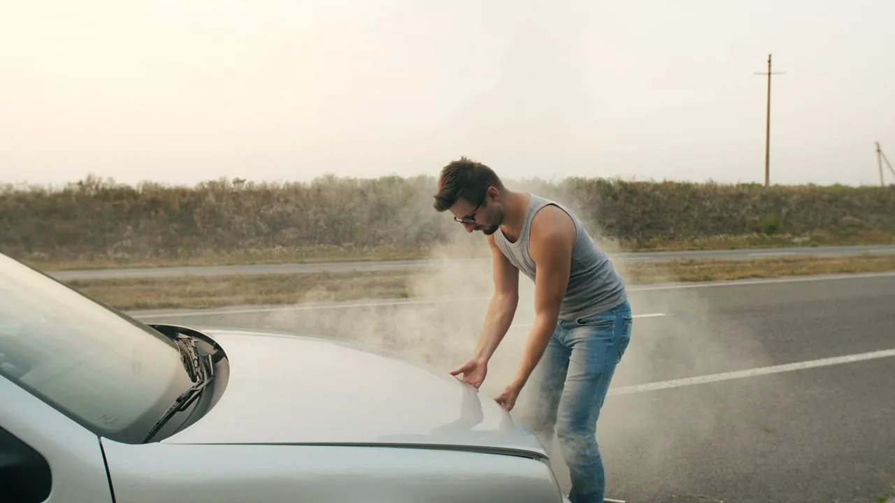 Driver checking steam rising from an overheated engine